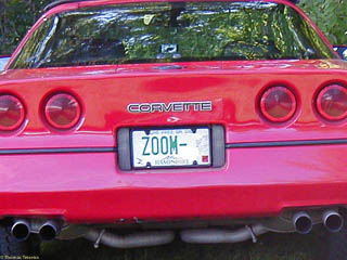 "ZOOM" license plate on the back of a red Corvette